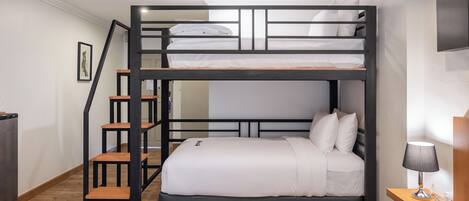 A bunk bed with a wooden ladder, a bedside table with a lamp, and a framed picture on the wall.