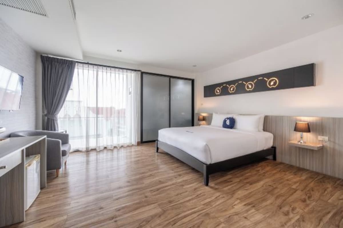 Una habitación de hotel moderna con una cama grande, un escritorio y vistas a la ciudad desde la ventana.