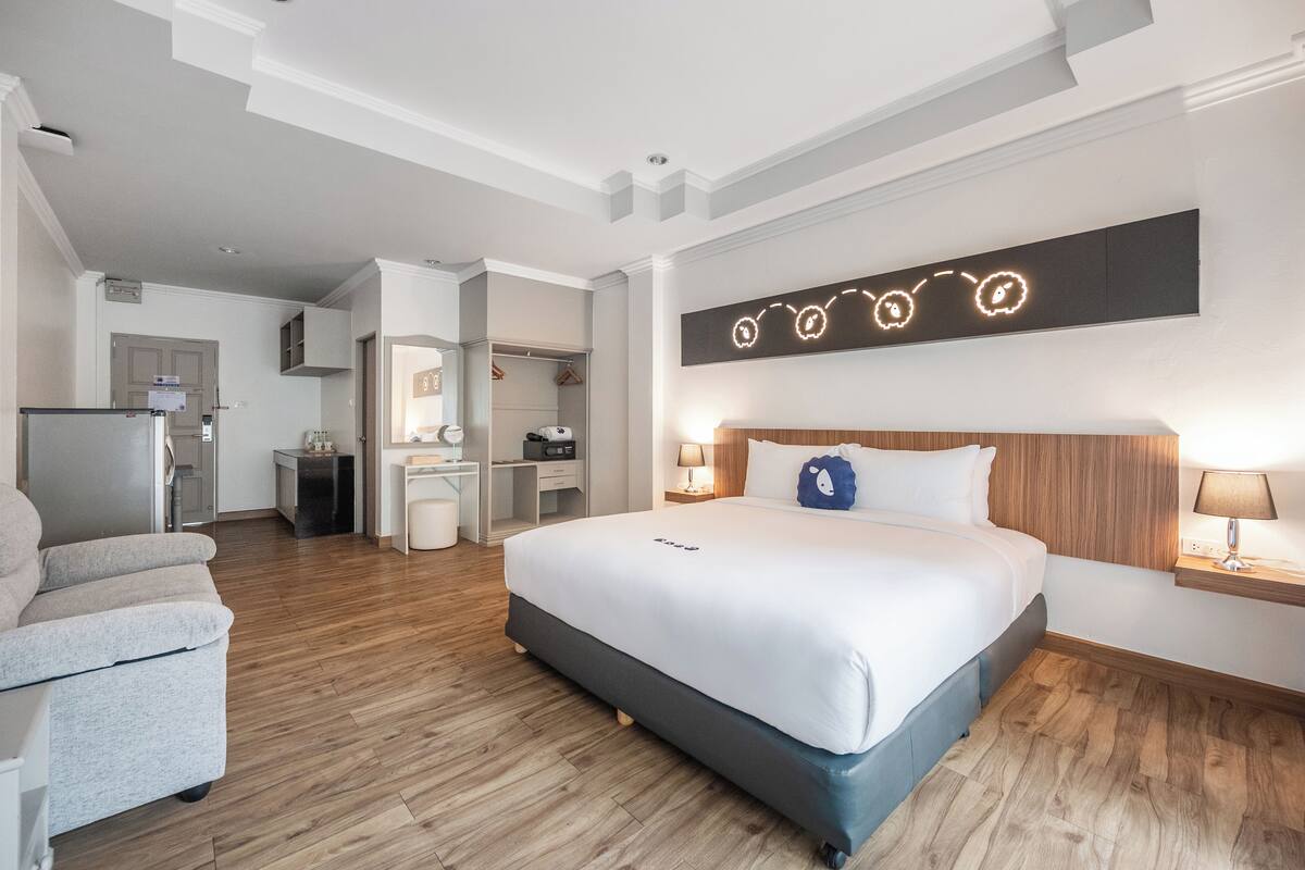 Una habitación de hotel con una cama grande, un escritorio, una silla y un rincón americano.