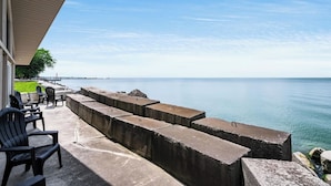 A waterfront patio with concrete planters, outdoor seating, and a view of the sea.