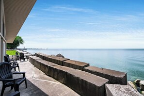 Une terrasse au bord de l’eau, agrémentée de jardinières en béton, de mobilier d’extérieur et offrant une vue sur la mer.