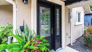 A house with a black front door, a security camera, and a garage door.