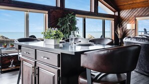 A modern kitchen with a large island, dark wood cabinets, and a view of the ocean.