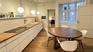 A modern kitchen with a wooden countertop, white cabinets, a round dining table, and pendant lights.
