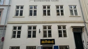 A multi-story building with a sign for 'BUURMESTERS GAARD' and a 'MATRAWS' shop on the ground floor.