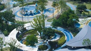An aerial view of a park with winding pathways, a central play area, and surrounding greenery. - Metropolo Jinjiang Hotel(Kunshan Jinying international Kunju theater store) (Kunshan)