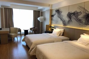 A hotel room with two beds, a desk, a chair, and a large abstract painting on the wall.