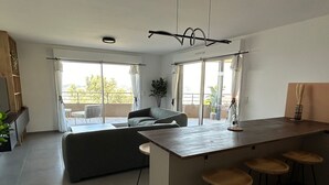 A modern kitchen with a central island, bar stools, and a dining area with a sofa.