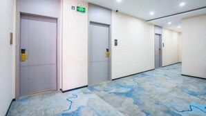 Un couloir d’hôtel avec des portes, une moquette à motifs et des panneaux indiquant les sorties de secours.