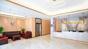Un hall d’hôtel moderne avec un comptoir d’accueil, un espace salon et un sol en marbre.