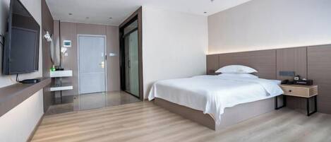 Quarto de hotel moderno com cama grande, mesa de cabeceira e televisão de tela plana na parede.
