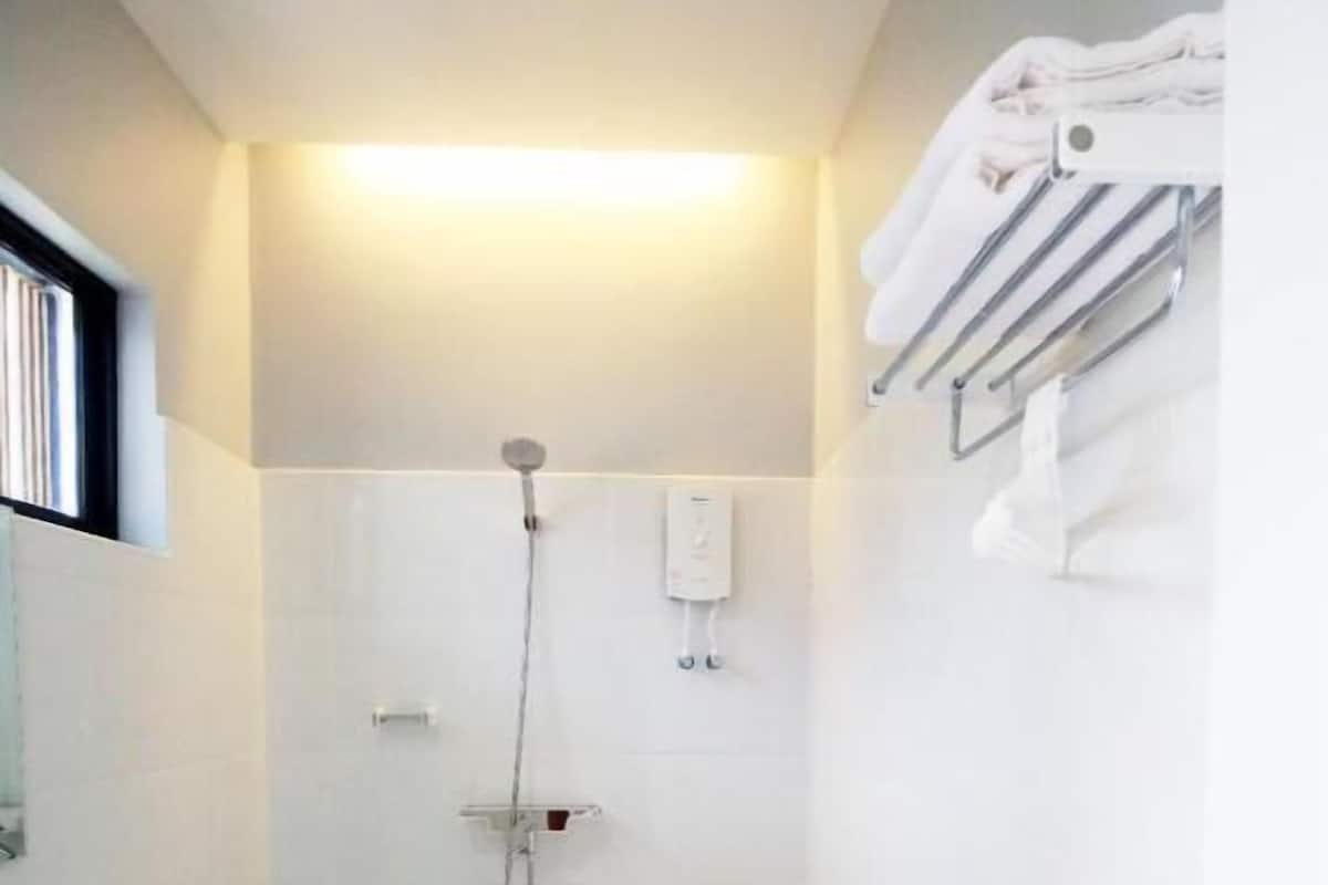 A small, white bathroom with a toilet, a shower, and a towel rack.