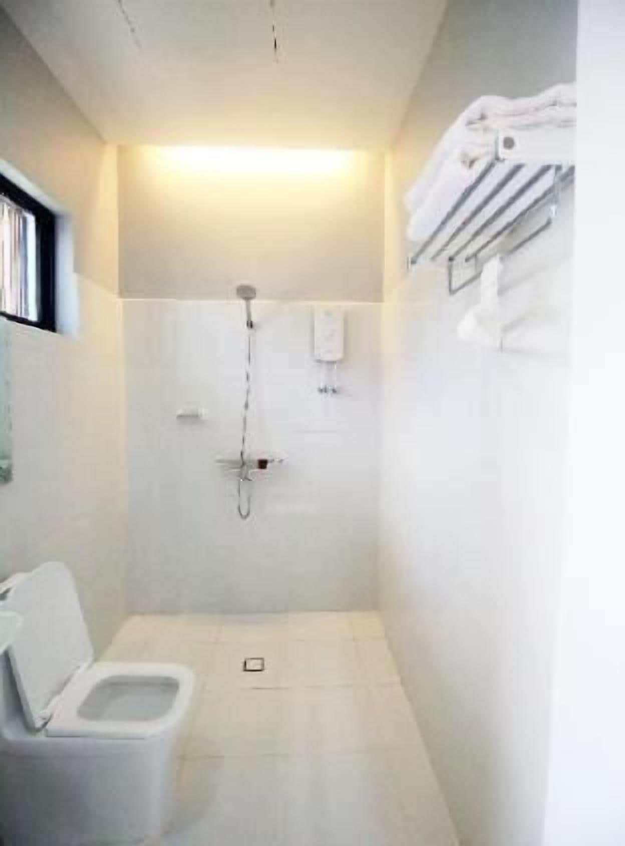 Ein kleines, weißes Badezimmer mit Toilette, Dusche und Handtuchhalter.