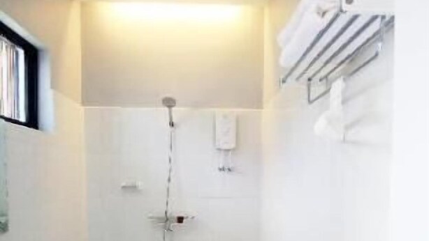 A small, white bathroom with a toilet, shower, and towel rack. - Bohol Casa Nino Hotel and Resort (Panglao Municipality)