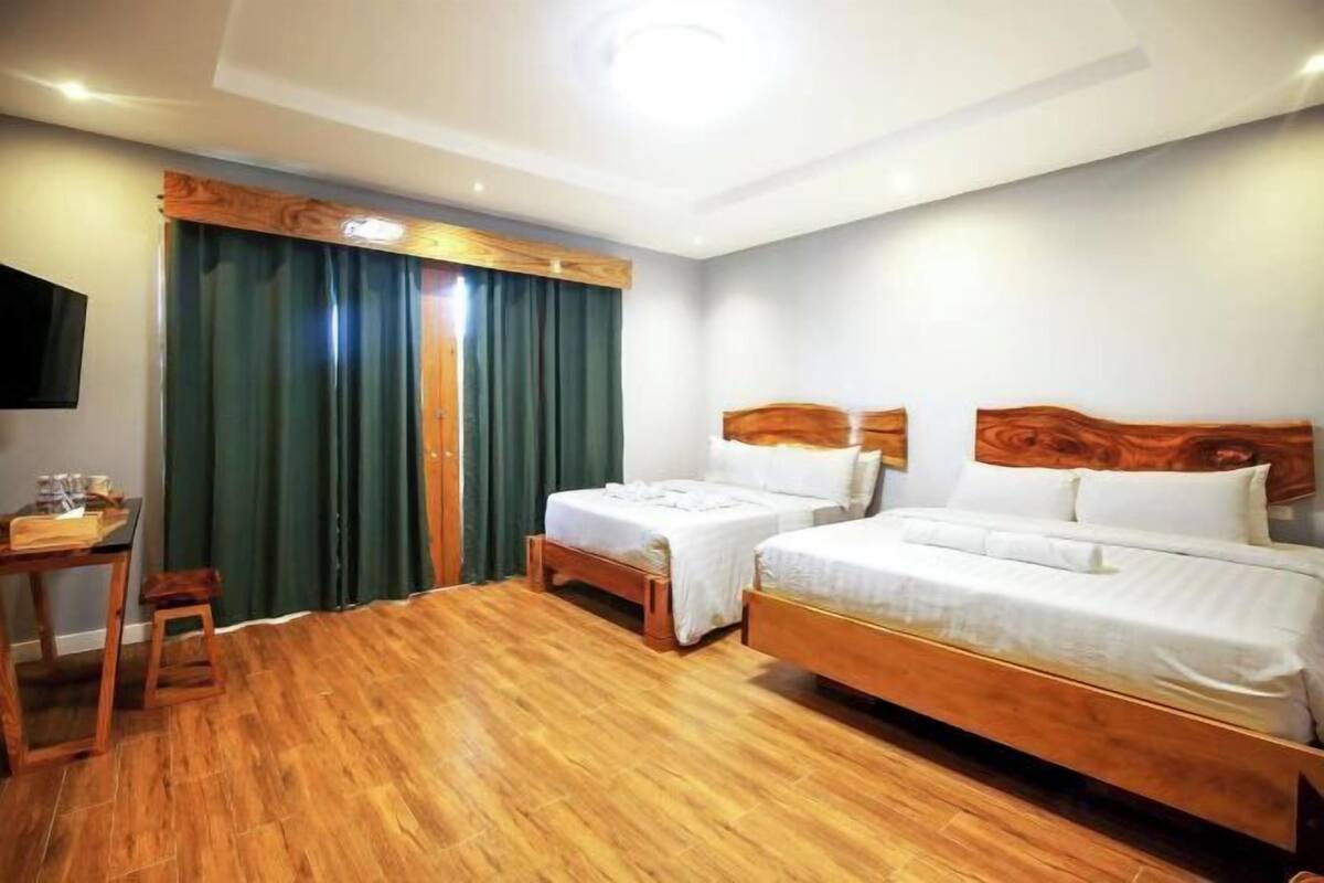 A hotel room with two beds, a desk, and a TV.