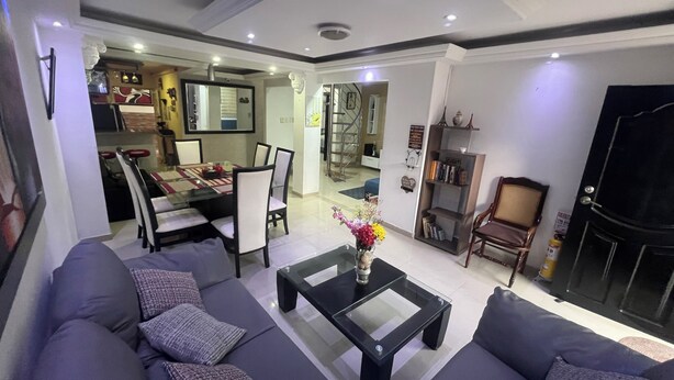 A modern living room with a sofa set, a coffee table, and a dining area with chairs and a table. - Casa Villa Carolina 5 min Puerta de Oro (Barranquilla)