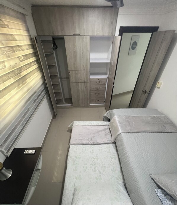 Un dormitorio pequeño con cama, armario y escritorio.