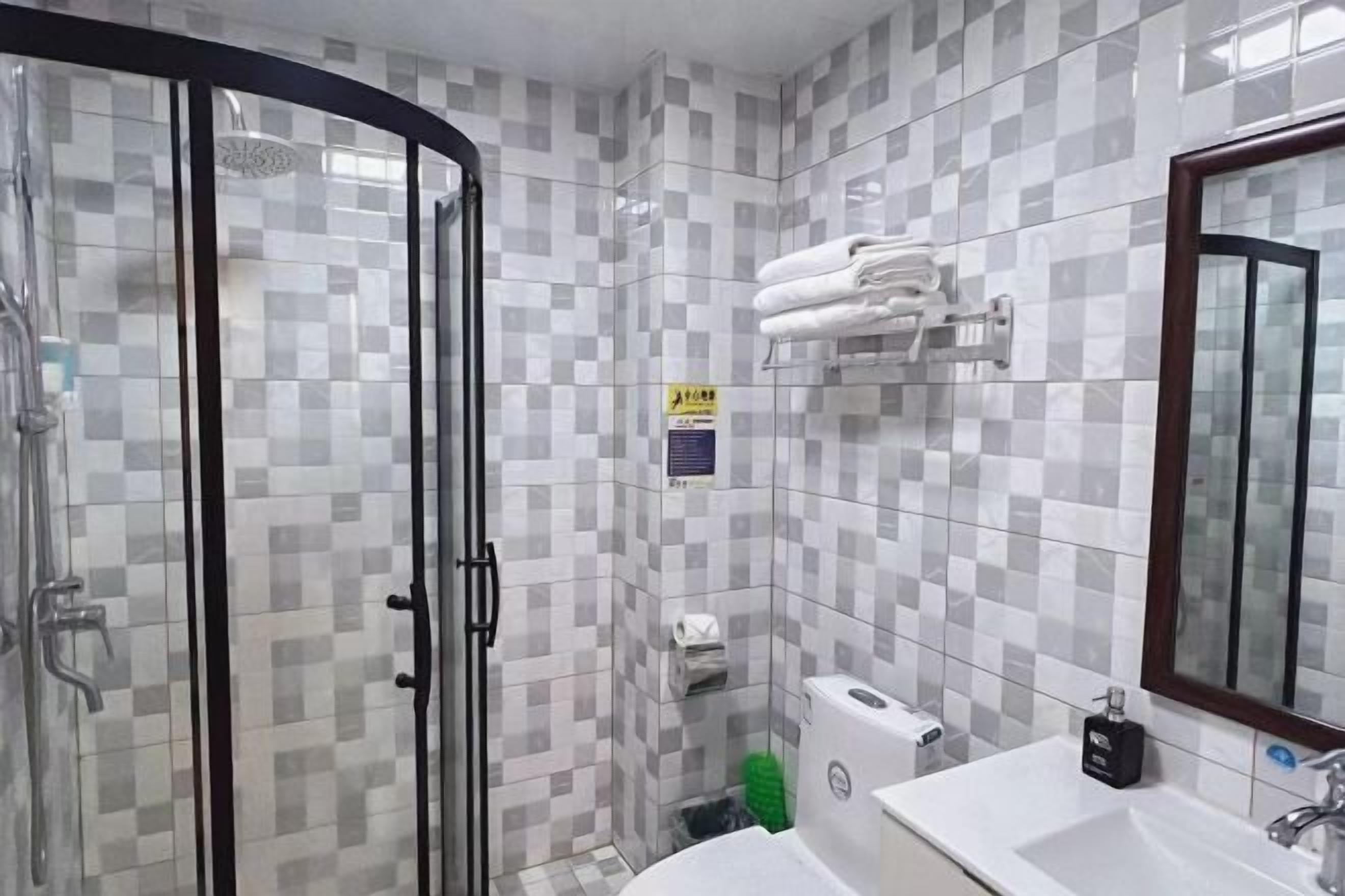 Une salle de bain avec une douche à parois de verre, un lavabo avec un miroir et un porte-serviettes.