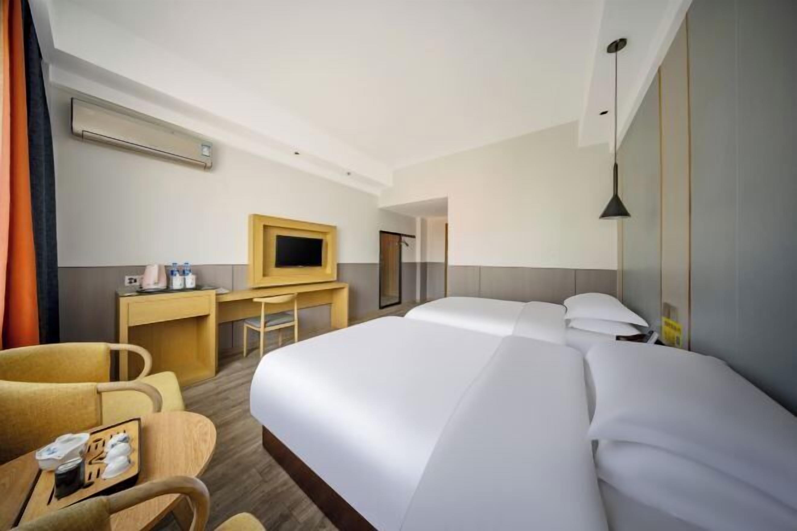 Une chambre d’hôtel avec un grand lit, un bureau avec une chaise, une télévision et un minibar.
