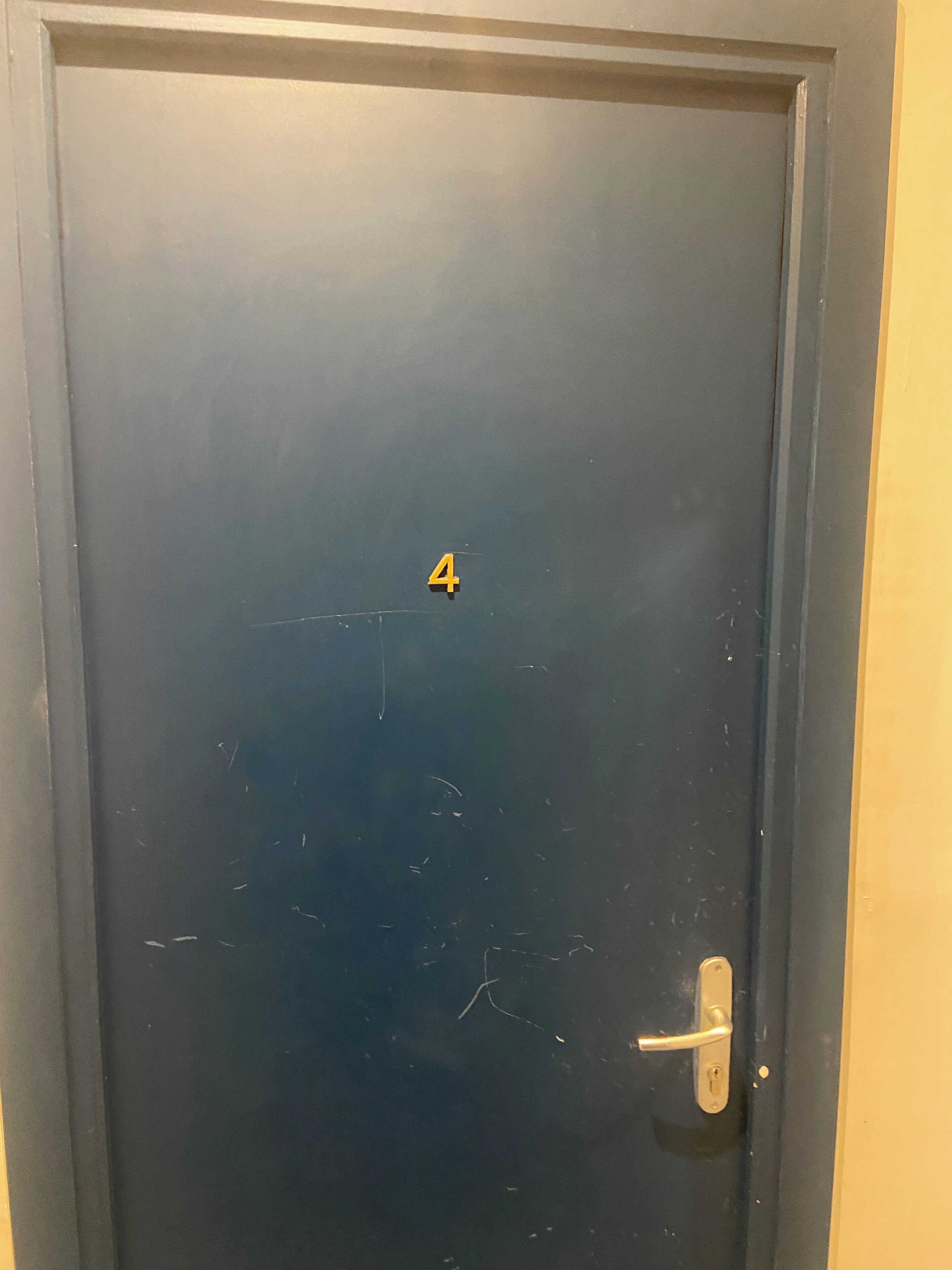 A dark-colored door with a small number '4' and a door handle.