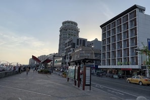 A city street with a bus stop, a tall building, and a yellow car. - Haitian Hotel (Zhoushan Shenjia Branch) (Zhoushan)