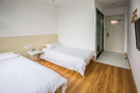 A hotel room with two single beds, a small bedside table with a phone, and a wooden floor. - Haitian Hotel (Zhoushan Shenjia Branch) (Zhoushan)
