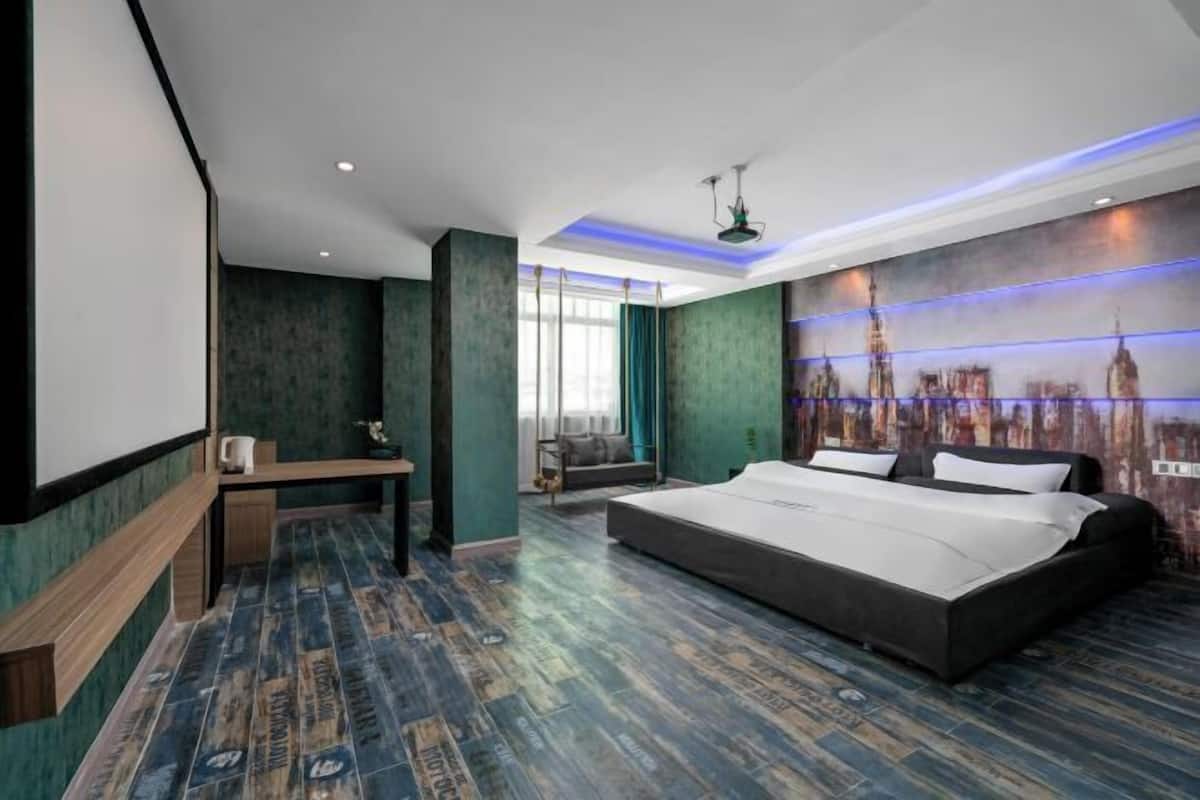Ein modernes Hotelzimmer mit einem großen Bett, einem Schreibtisch und einem Wandgemälde mit Stadtansicht.