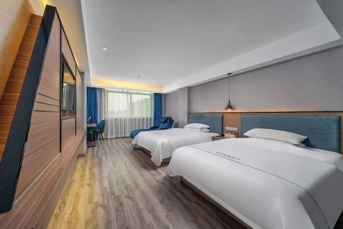Ein Hotelzimmer mit zwei Betten, einem Schreibtisch und einem Stuhl.