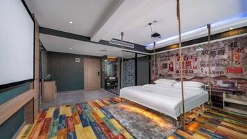 A modern hotel room with a bed, a colorful striped carpet, a large mirror, and a wall with motivational posters.