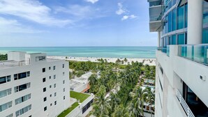 Ein Hochhaus-Hotel mit Blick auf einen Strand, Palmen und einen klaren Himmel.
