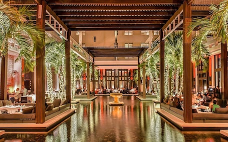 A spacious indoor area with a central water feature, surrounded by seating areas and palm trees.