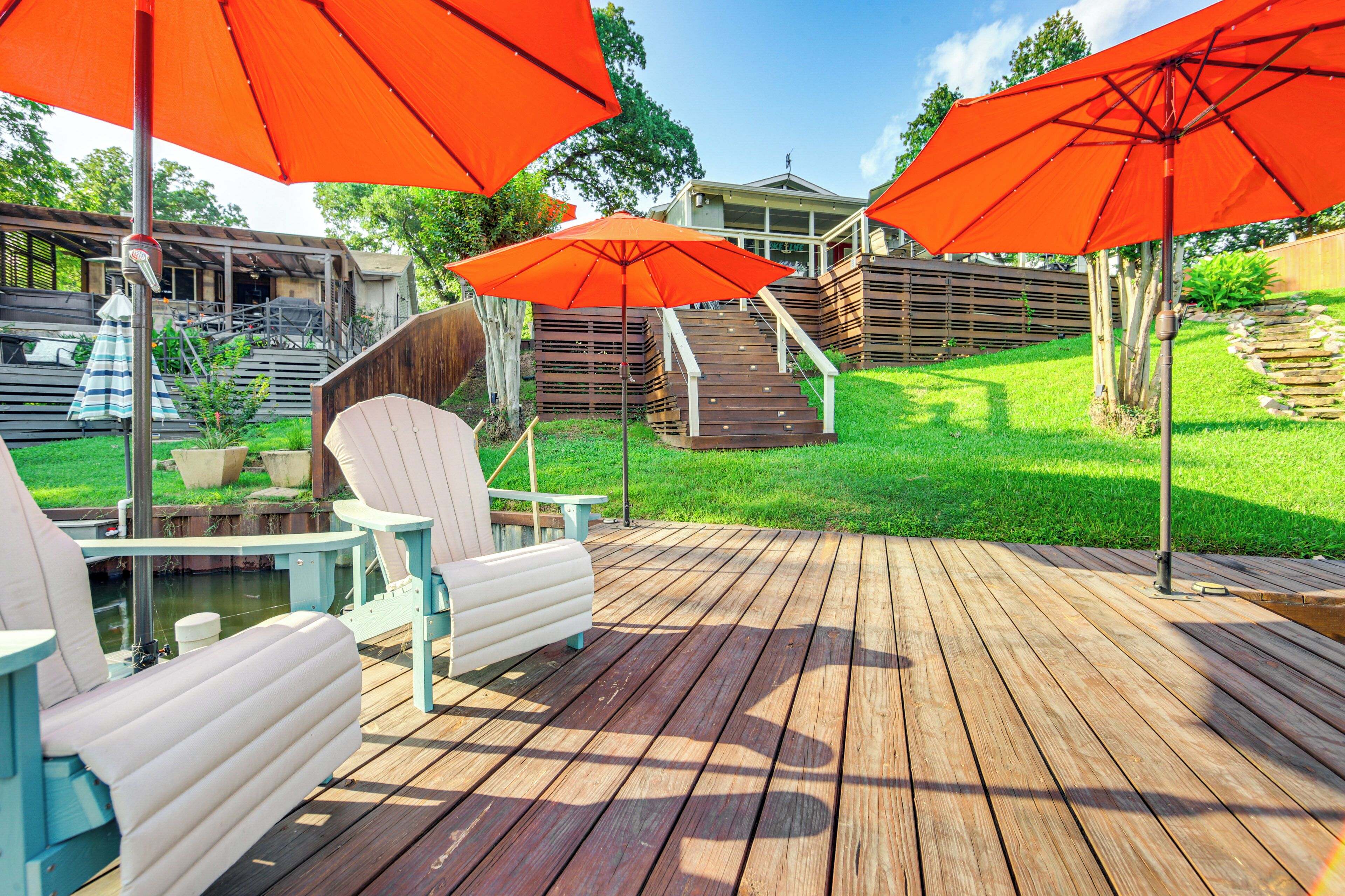Una terraza de madera con mobiliario exterior y sombrillas rojas.