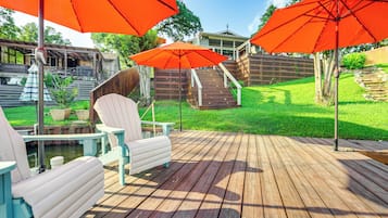 Una terraza de madera con mobiliario exterior y sombrillas rojas.