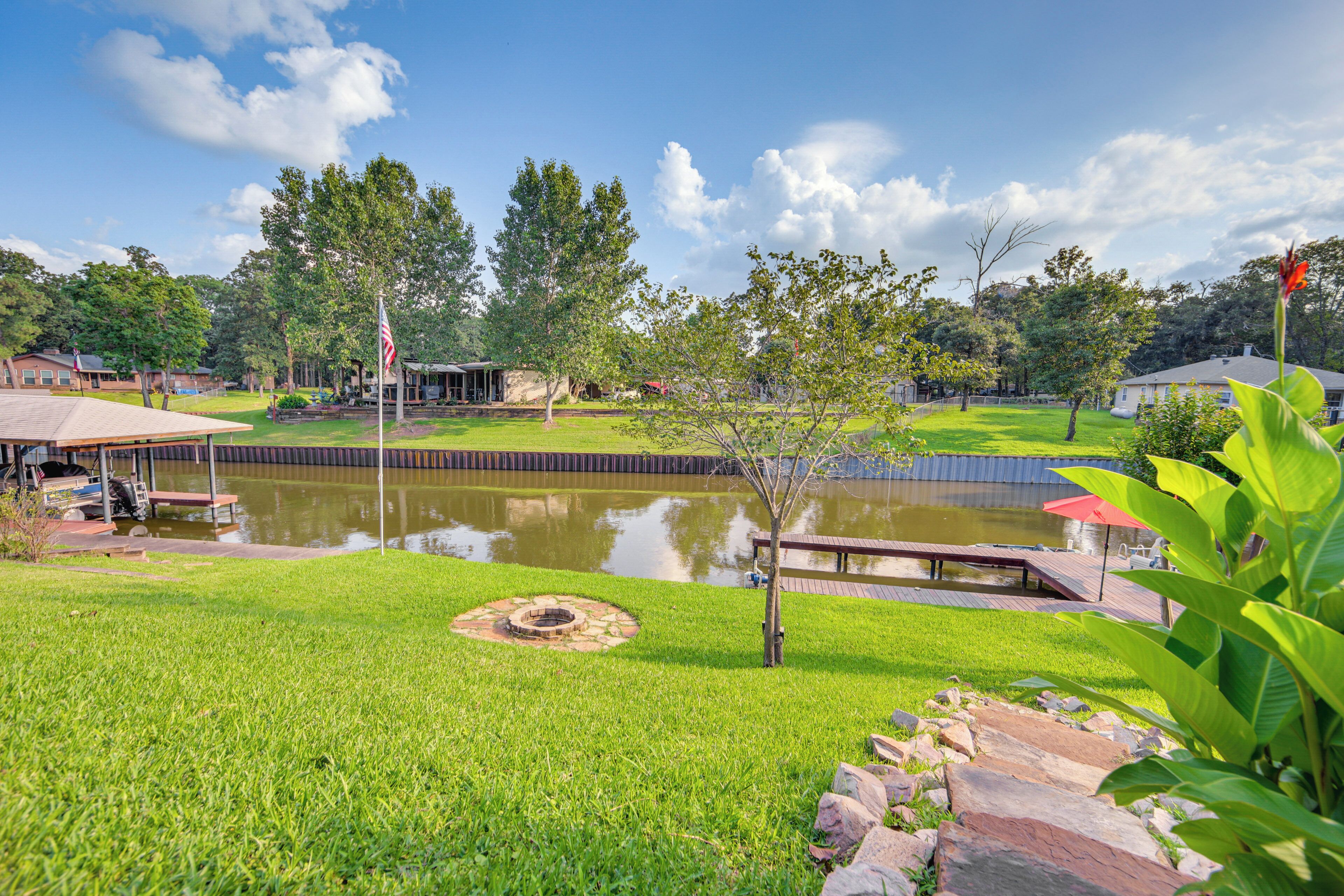 A well-maintained grassy area with a pond, a wooden deck, and a flagpole.