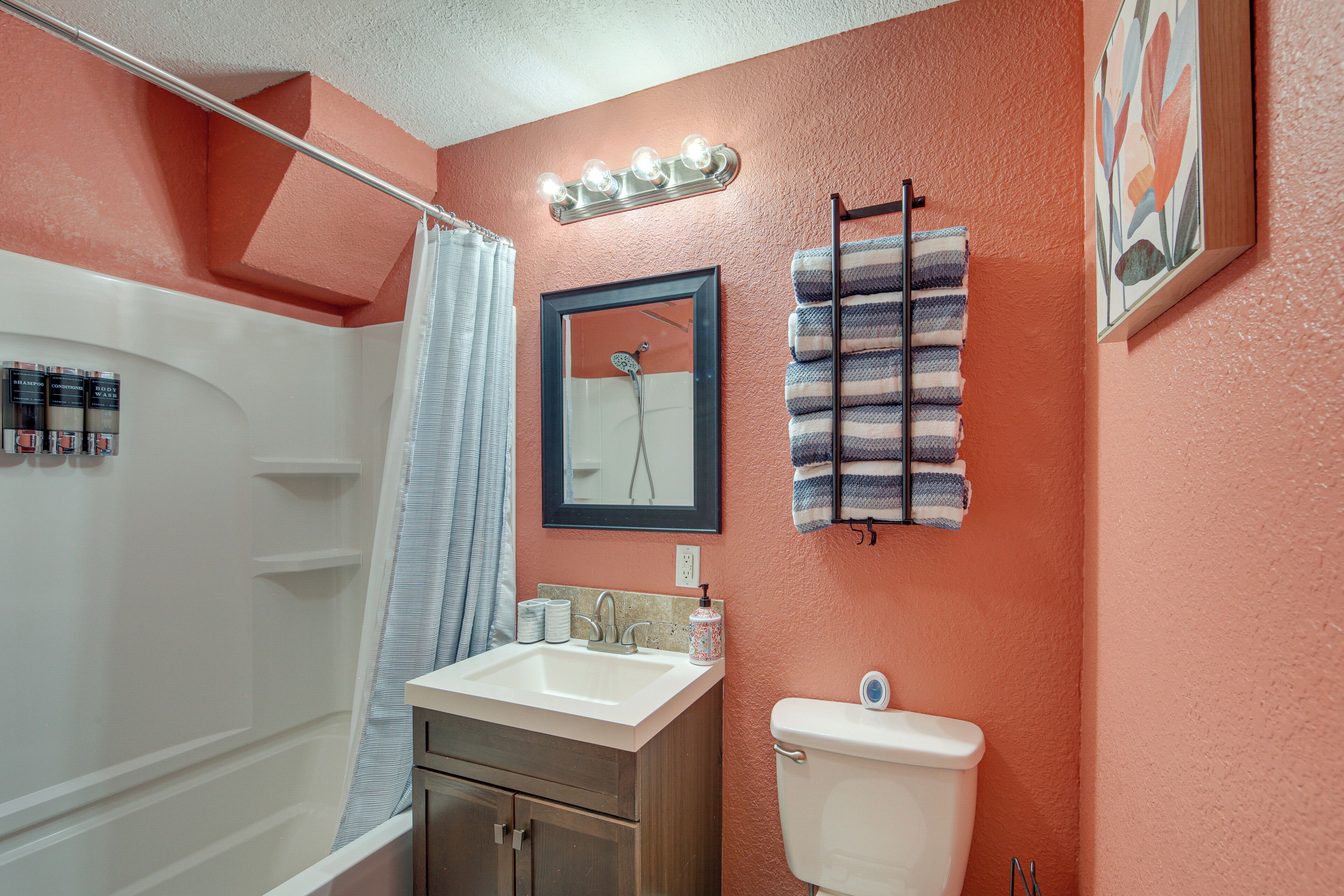 A bathroom with a white sink, a toilet, a shower, and a towel rack.