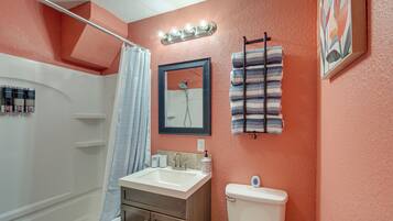 A bathroom with a white sink, a toilet, a shower, and a towel rack.