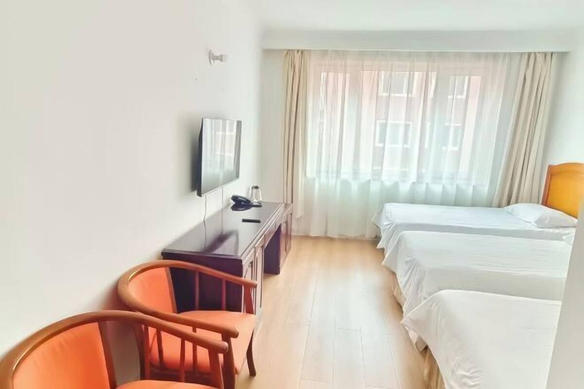 A hotel room with a bed, a desk, a chair, and a television.