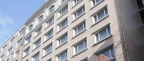 Un edificio de varios pisos con fachada uniforme, muchas ventanas y techo plano.