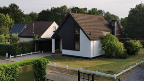 A modern house with a sloped roof, a covered porch, and a well-maintained lawn. - Heavenly vacation home near the sea (Bruinisse)