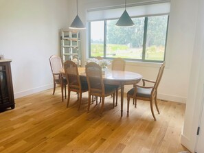 A dining area with a round wooden table, four chairs, and pendant lights. - New Luxury Escape, Mountain Views, Pool & River Access!  (Star)