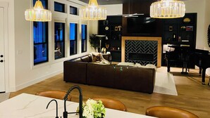 A modern living room with a dark brown sofa, a fireplace, and a dining area with a table and chairs.