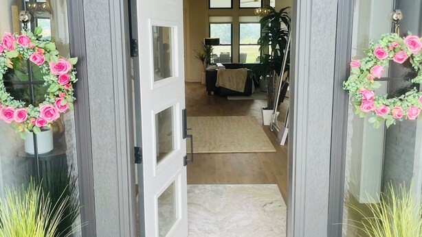 A doorway leading into a room with a chandelier, potted plants, and a view of the interior.