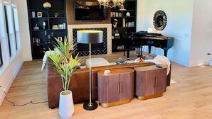 A modern living room with a sectional sofa, a large floor lamp, a piano, and a bookshelf.
