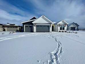 A modern two-story house with a garage, a driveway, and a snow-covered landscape. - New Luxury Escape, Mountain Views, Pool & River Access!  (Star)