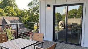 A covered patio with a table and chairs, a sliding glass door, and a view of the surrounding area. - Terrace View Apartment (Moscow)