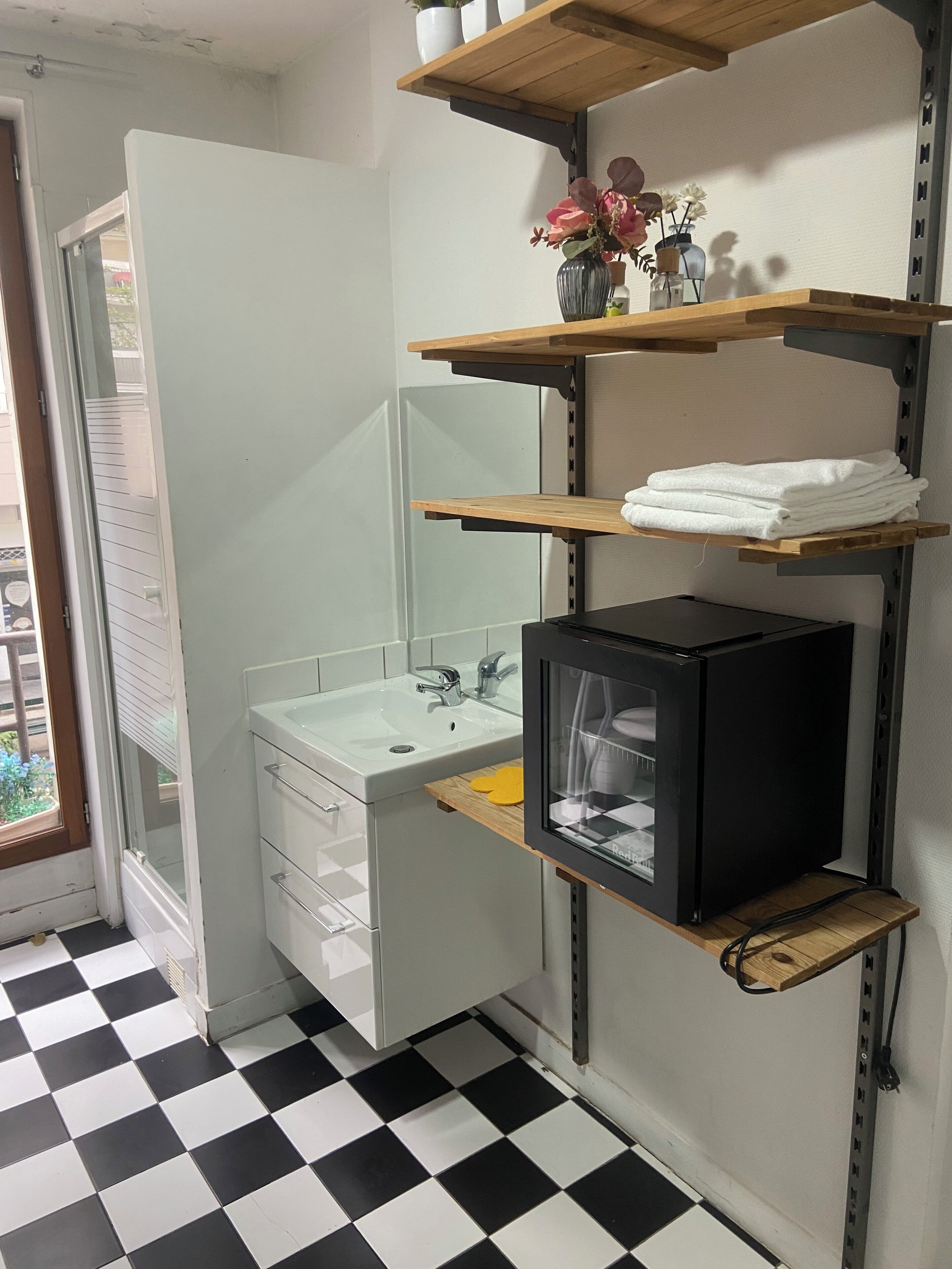 A bathroom with a black and white checkered floor, a white sink, a mirror, and a black cabinet.
