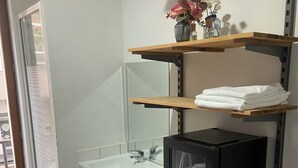 A bathroom with a black and white checkered floor, a white sink, a mirror, and a black cabinet. - Room in Montmartre with privat shower and shared WC (PARIS 18)