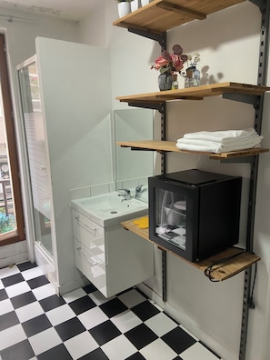 A bathroom with a black and white checkered floor, a white sink, a mirror, and a black cabinet. - Room in Montmartre with privat shower and shared WC (PARIS 18)