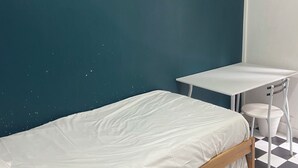 Une chambre avec un lit simple, une petite table et une chaise.