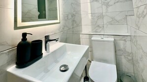 Une salle de bain moderne avec un grand miroir, un lavabo blanc et des toilettes.